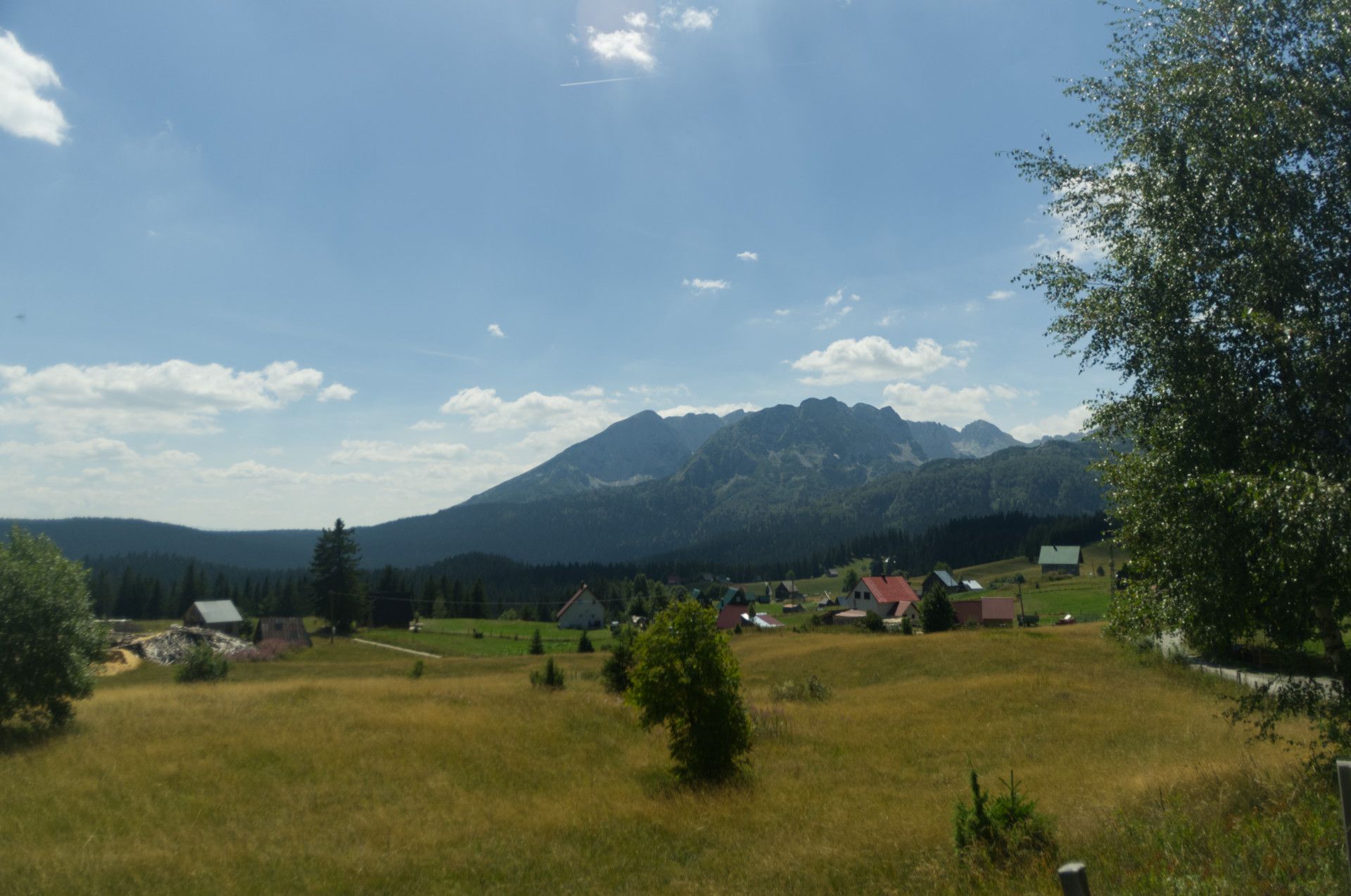 A photo of an open field with a village and a far view behind